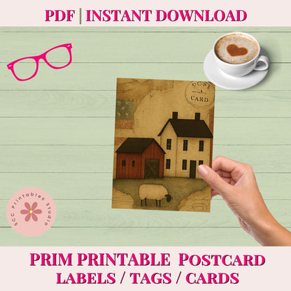 Hand holding a postcard with houses and sheep, with a cup of coffee and glasses on a wooden surface.