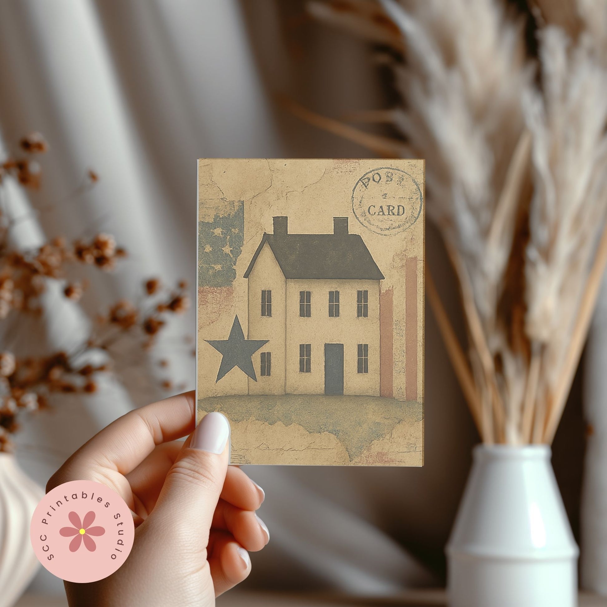 Hand holding a vintage-style house card with decorative elements in the background