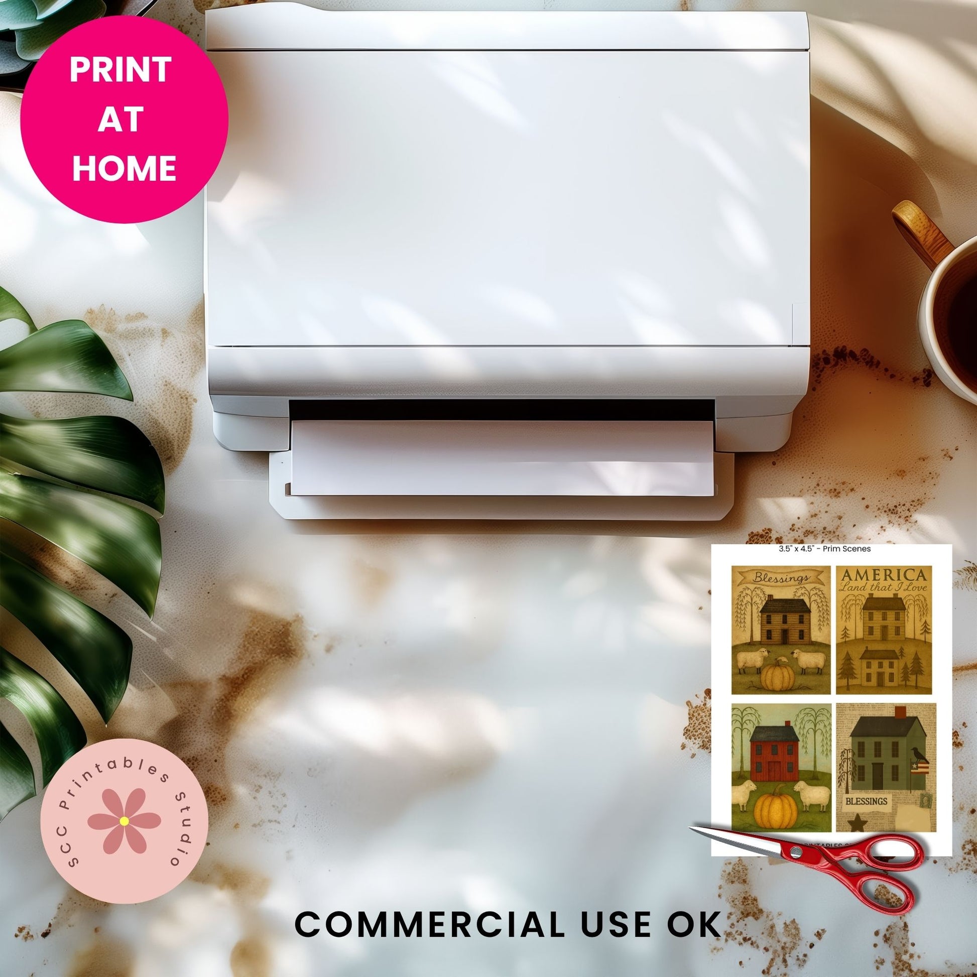 A white desktop printer shown from above on a marble-like surface with decorative props, including a pink 'PRINT AT HOME' badge, a plant leaf, a cup, and a sample print preview with the text 'COMMERCIAL USE OK' and 'KCC Printables Studio'.