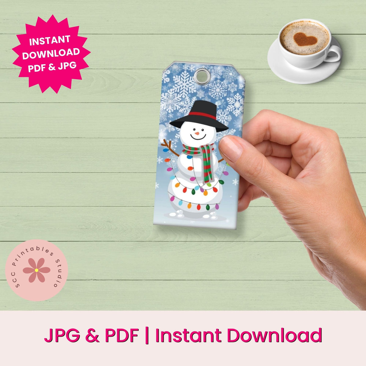 A hand holds a phone case featuring a festive snowman design with a black hat, red scarf, and colorful holiday lights on a light blue snowflake background. The scene is set against a light green wood-plank backdrop with promotional text reading 'Instant Download PDF & JPG' and 'JPG & PDF | Instant Download'.
