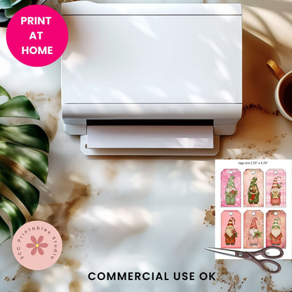 A white desktop printer shown on a styled marble surface with a pink 'PRINT AT HOME' badge, a pink circular 'SCC Printables Studio' logo, scissors, a coffee cup, and a small preview of gnome-themed printable tags. Text at the bottom reads 'COMMERCIAL USE OK'.