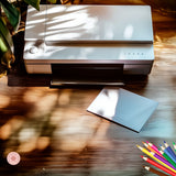 Printer on a wooden surface with a sheet of paper and colorful pencils nearby