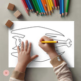 Child coloring a fish outline with colored pencils on a gray surface