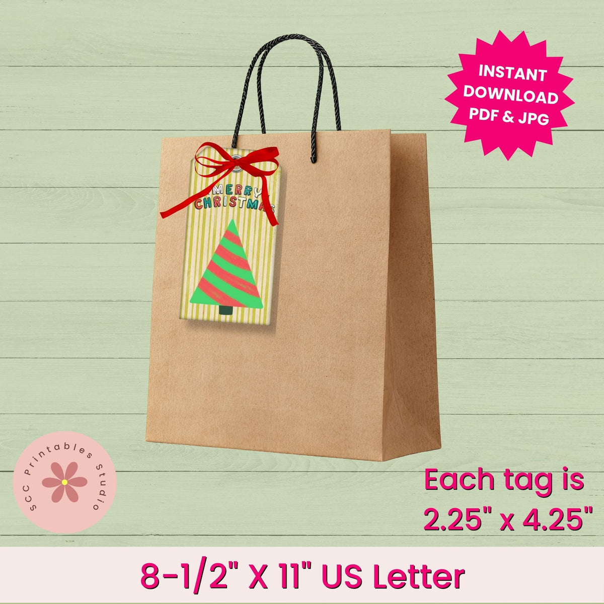 A printable gift tag template shown attached to a brown paper bag with black handles. The tag has a yellow striped background, a green and red Christmas tree design, and a black bow.