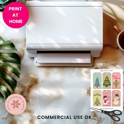 A white desktop printer shown on a marble surface with a pink 'PRINT AT HOME' badge, a pink 'SCC Printables Studio' logo, a sample holiday print sheet, and scissors nearby.
