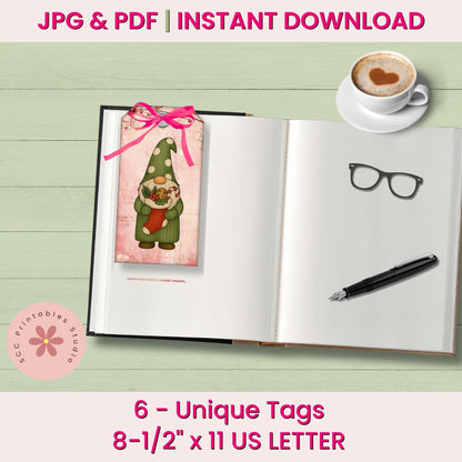 Digital mockup showing a printable bookmark/tag design with a gnome illustration and pink ribbon, placed on an open notebook with a coffee cup, glasses, and pen. Text reads 'JPG & PDF | INSTANT DOWNLOAD' and '6 - Unique Tags 8-1/2" x 11 US LETTER'.