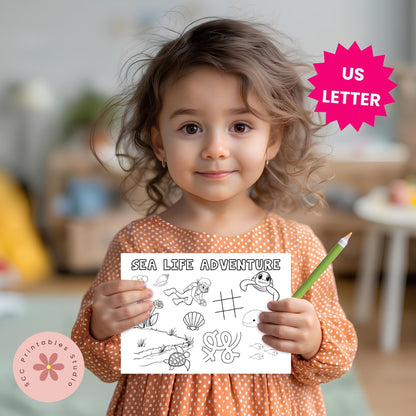 Child holding a coloring sheet titled 'Sea Life Adventure' with a pencil, in a home setting.