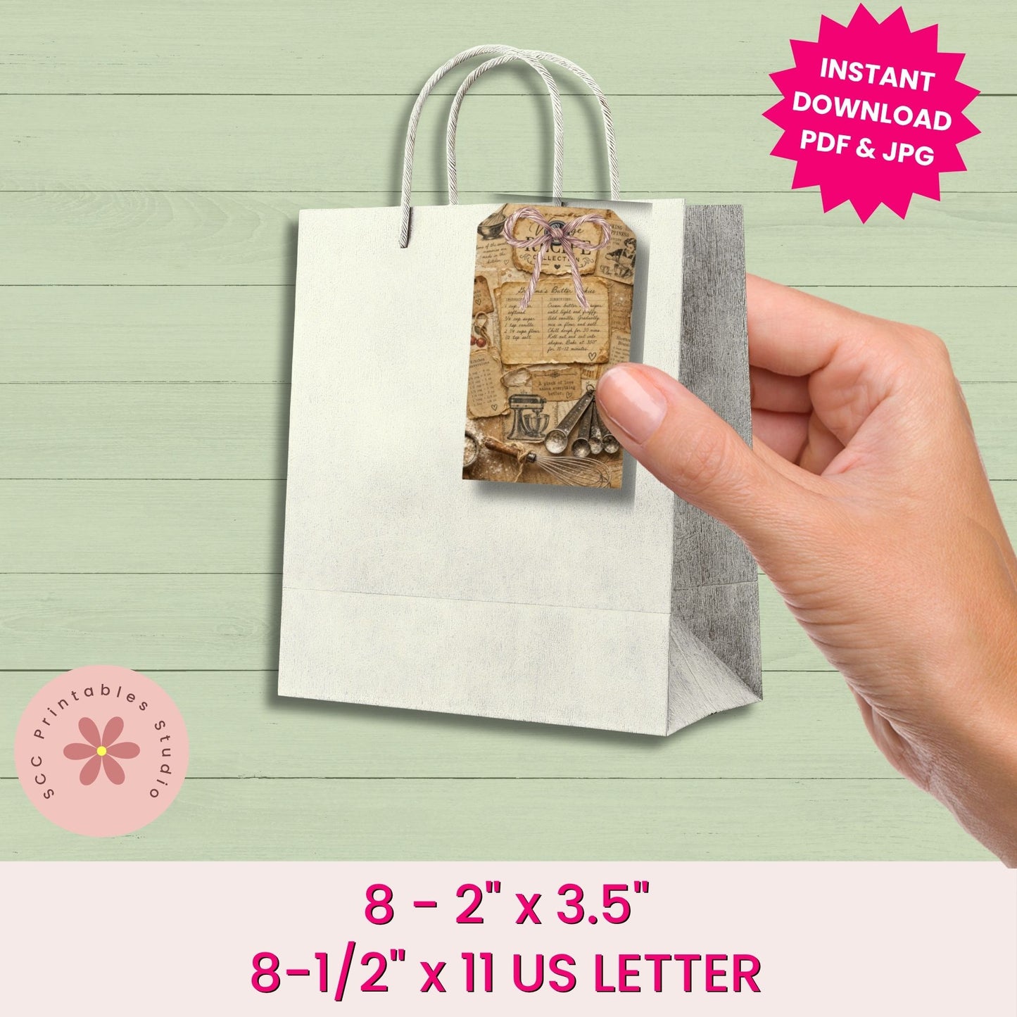 Hand holding a small paper bag with a printed design on a light green wooden surface.