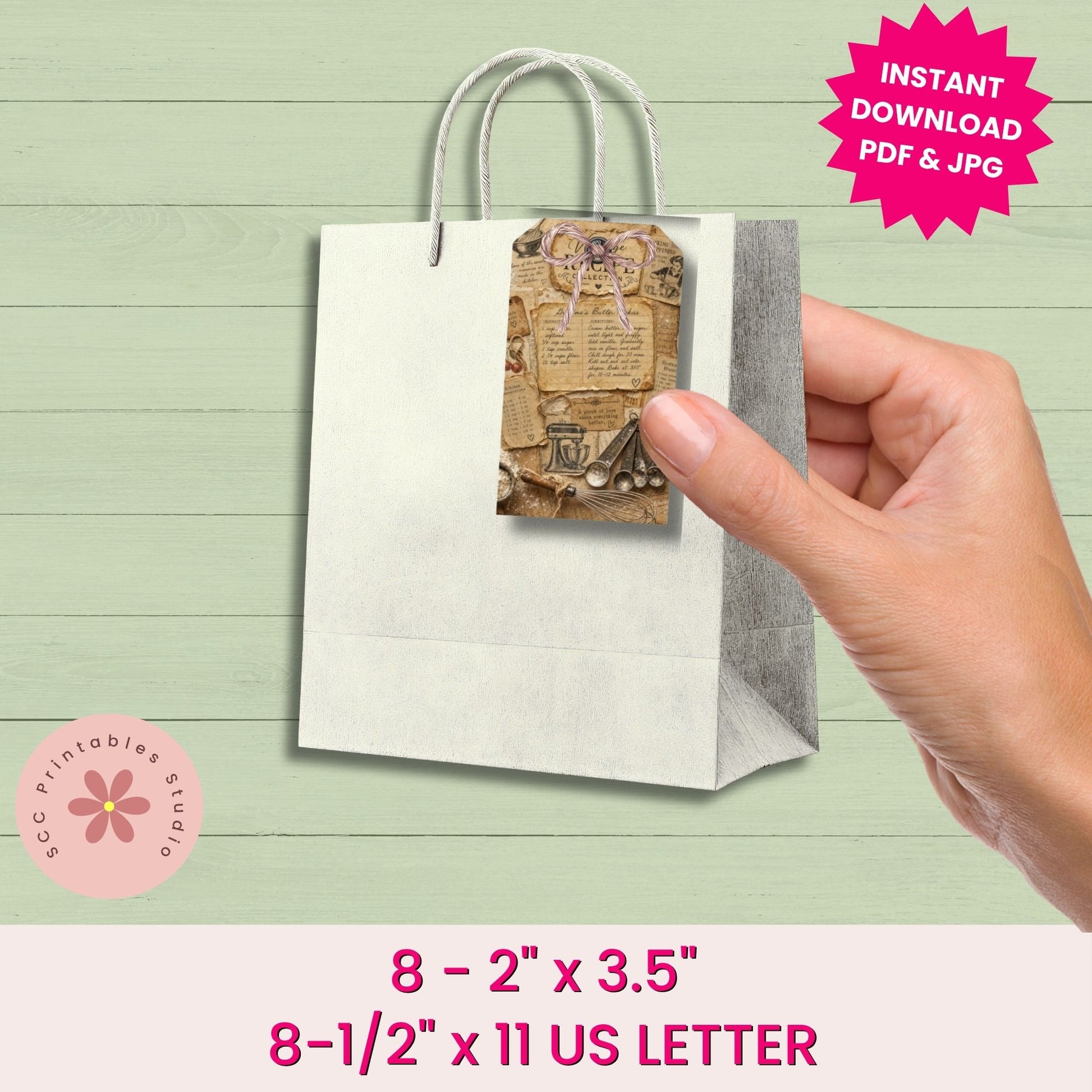 Hand holding a small paper bag with a printed design on a light green wooden surface.